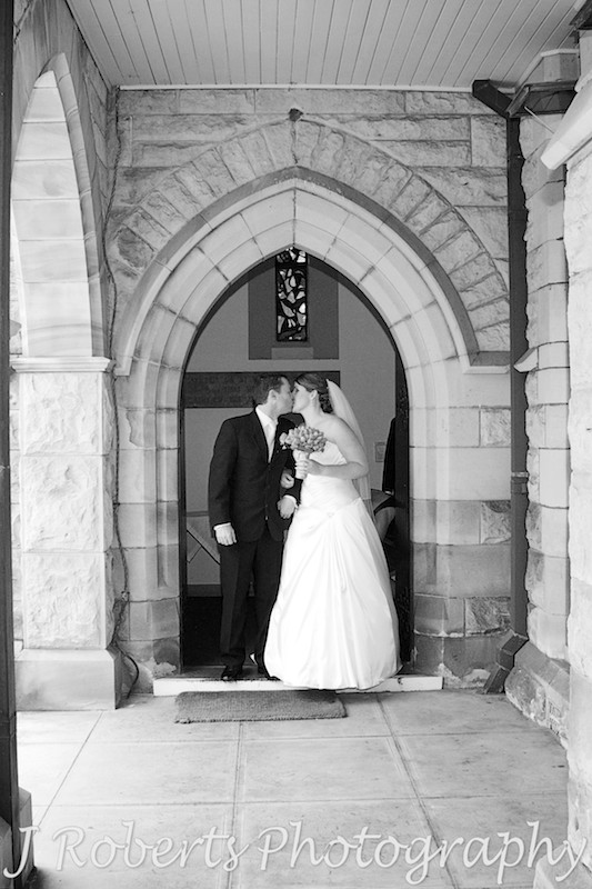 Bride and groom kissing on church steps - wedding photography sydney